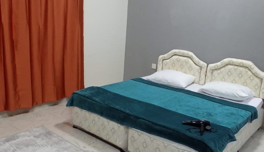 دو تخت یک نفره با پرده و سشوار در اتاق شماره ۸ هاستل ماندگار در مسقط، عمان