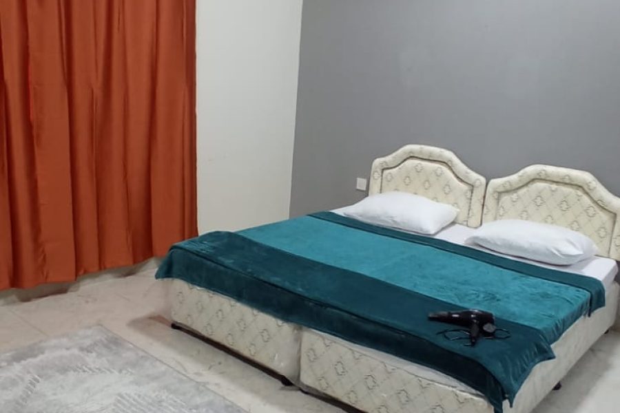دو تخت یک نفره با پرده و سشوار در اتاق شماره ۸ هاستل ماندگار در مسقط، عمان